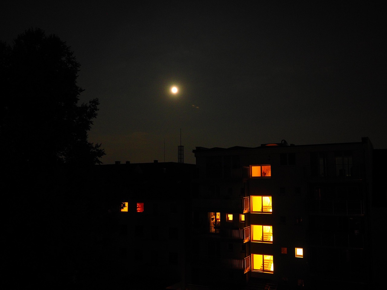 Apartment building at night with a few windows still lit