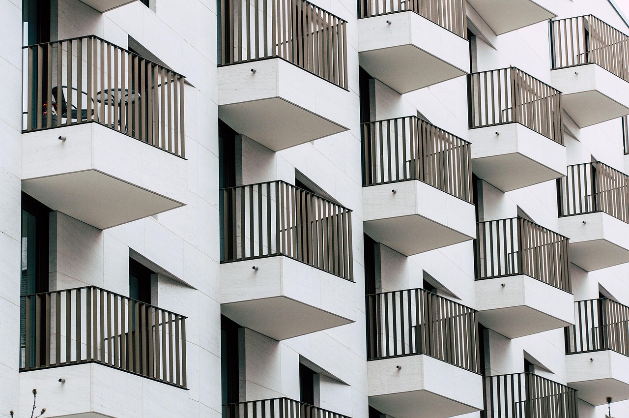 Pale stone facade of an apartment building with bronze balcony railings